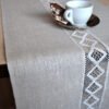 Linen table runner with lace on the middle along of the runner. And the lace is see though the table.