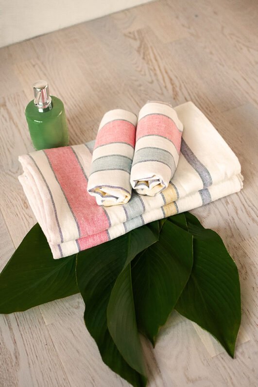 Off white heavy linen towels for hands, face or guests, to use in the bathroom. Off white towels are with pastel colors stripes.