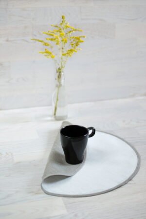 Round linen placemats with a reversible design, one side off-white and the other natural linen, with a natural linen border.