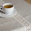 beige linen table runner with off white linen lace in the center, the table see through.