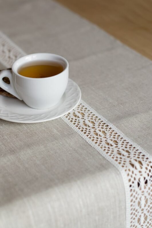 beige linen table runner with off white linen lace in the center, the table see through.