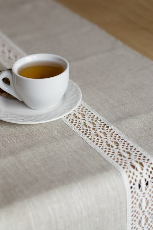 beige linen table runner with off white linen lace in the center, the table see through.