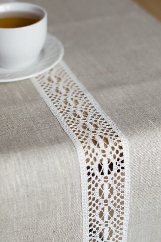 beige linen table runner with off white linen lace in the center, the table see through.