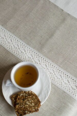 beige linen table runner with off white linen lace in the center, the table see through.