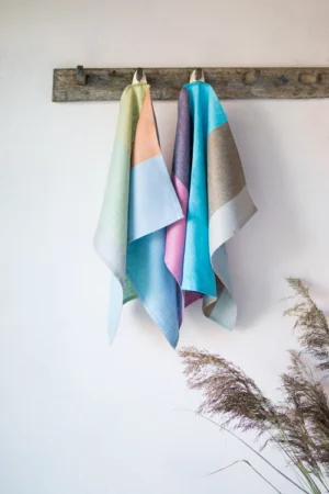 Set of 2 colorful striped linen towels. One with pastel colors wide stripes, the other with bright hues. Pastel towel with light green mint color, light blue, light citrus lemonade, cinnamon, and pastel blue hue. The other the towel from the set with brighter hues - Bright pink, eggplant color, Turquoise blue, and coffee latte brown wide stripes.