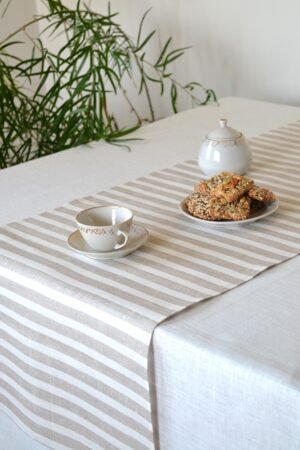 Short natural striped linen table runner with stripes goes across the runner.