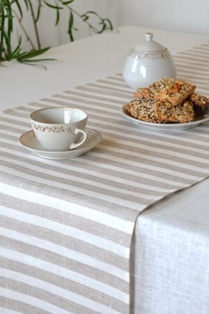 Short natural striped linen table runner with stripes goes across the runner.
