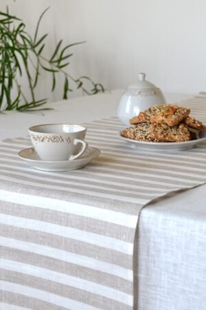 Short natural striped linen table runner with stripes goes across the runner.