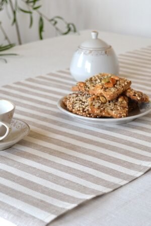 Short natural striped linen table runner with stripes goes across the runner.