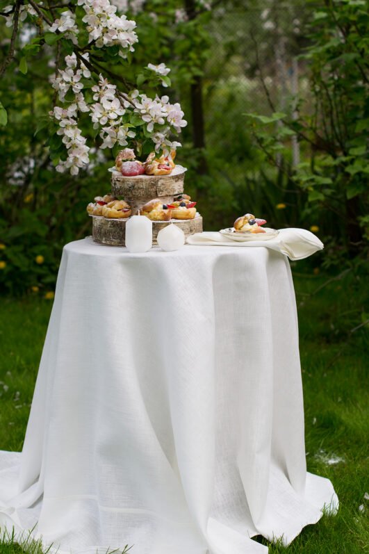 Off white round linen tablecloth on small table goes to the ground in so wonderful deep folds. This linen tablecloth layers on the ground looks so luxury. It is so elegant for Your party in the garden or at home.