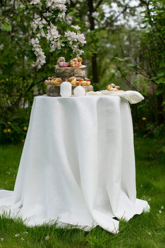 Off white round linen tablecloth on small table goes to the ground in so wonderful deep folds. This linen tablecloth layers on the ground looks so luxury. It is so elegant for Your party in the garden or at home.