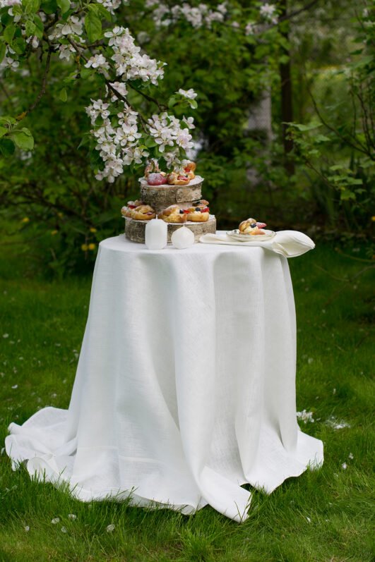 Off white round linen tablecloth on small table goes to the ground in so wonderful deep folds. This linen tablecloth layers on the ground looks so luxury. It is so elegant for Your party in the garden or at home.