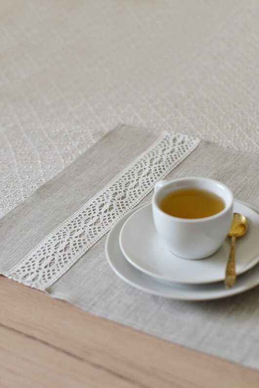Light natural linen placemat with off-white lace trim, elegant table setting.