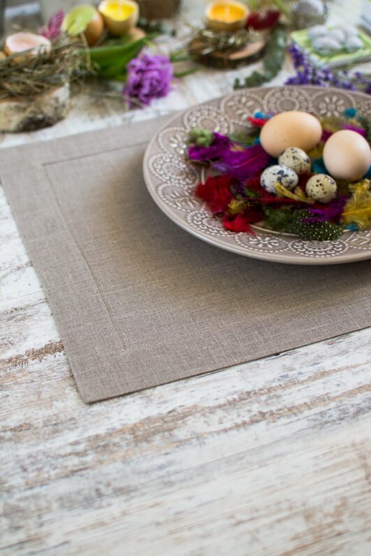 Elegant linen placemats in neutral tones (natural, light natural, off-white) with wide mitered corners. Perfect for casual or formal dining. Shop now for simple, natural table decor.