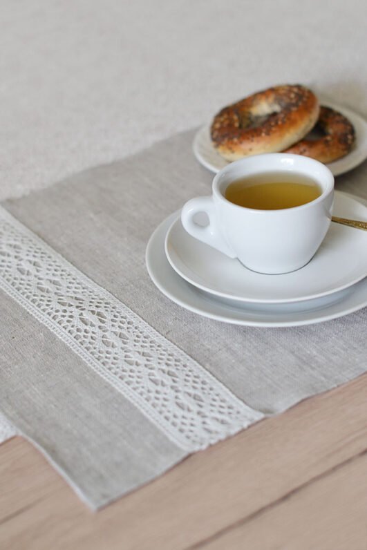 Light natural linen placemat with off-white lace trim, elegant table setting.