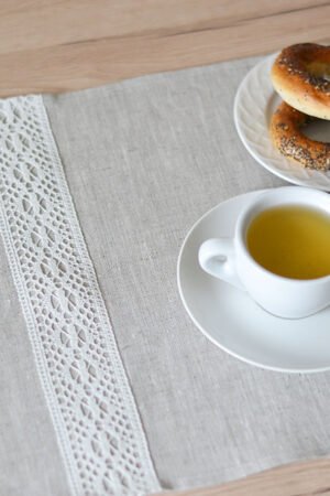 Light natural linen placemat with off-white lace trim, elegant table setting.