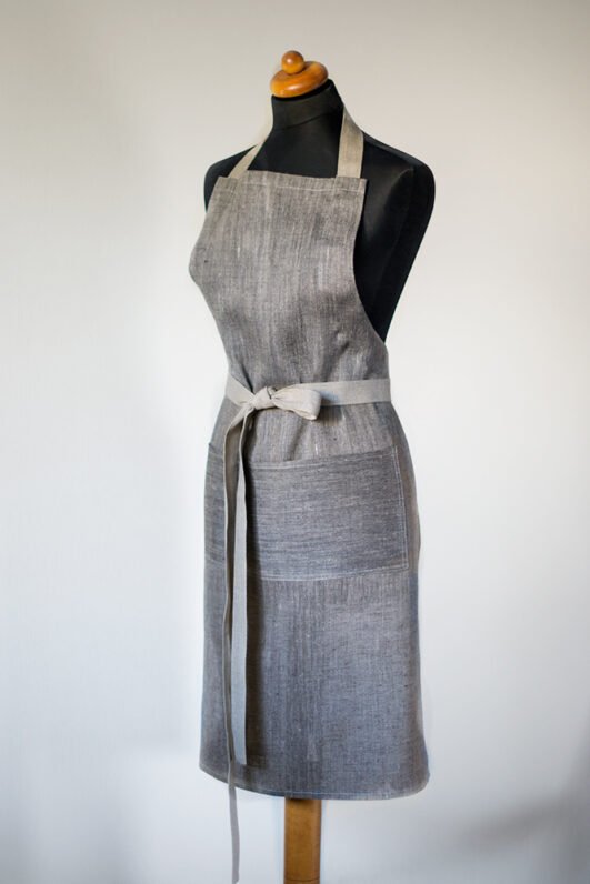 Grey linen apron made from melange linen - black with natural linen yarns. The belt is adjustable and made from natural linen. One big pocket on front.