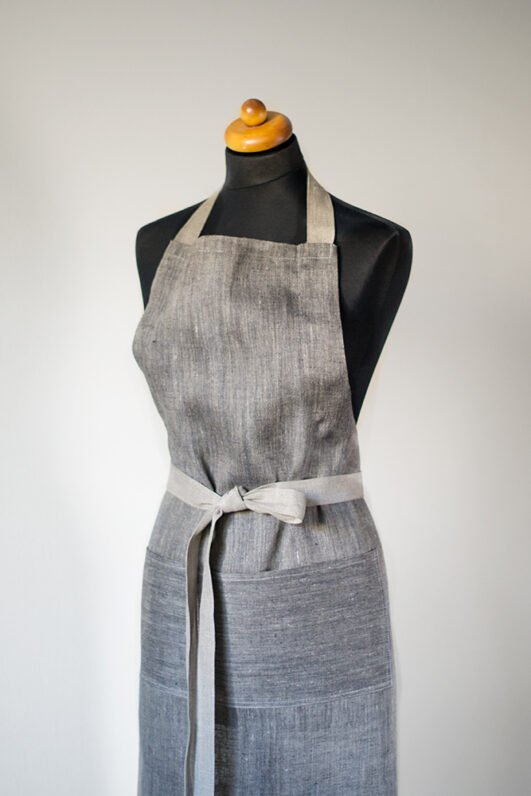 Grey linen apron made from melange linen - black with natural linen yarns. The belt is adjustable and made from natural linen. One big pocket on front.