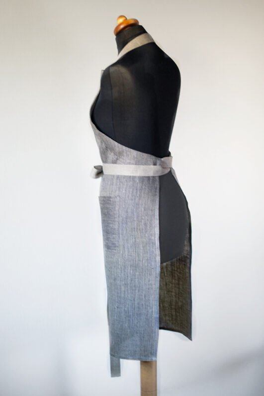 Grey linen apron made from melange linen - black with natural linen yarns. The belt is adjustable and made from natural linen. One big pocket on front.