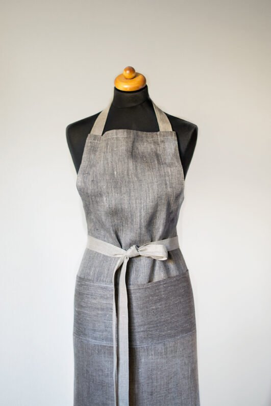 Grey linen apron made from melange linen - black with natural linen yarns. The belt is adjustable and made from natural linen. One big pocket on front.