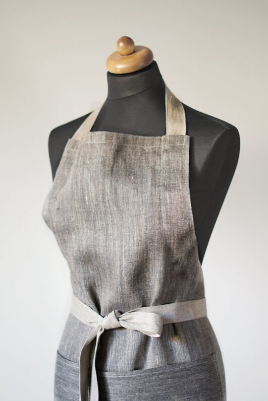 Grey linen apron made from melange linen - black with natural linen yarns. The belt is adjustable and made from natural linen. One big pocket on front.