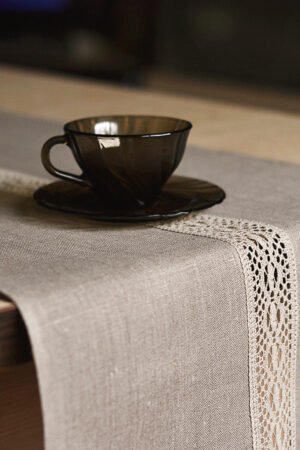 Natural tan linen table runner with a decorative linen lace trim through the middle.