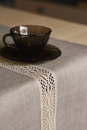 Natural tan linen table runner with a decorative linen lace trim through the middle.