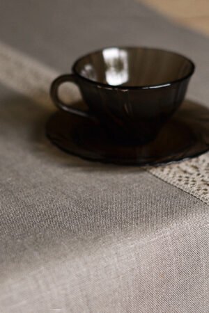 Natural tan linen table runner with a decorative linen lace trim through the middle.