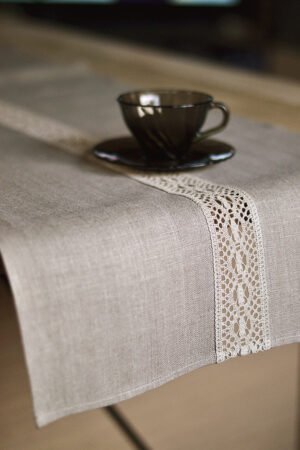 Natural tan linen table runner with a decorative linen lace trim through the middle.