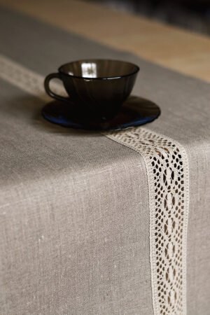 Natural tan linen table runner with a decorative linen lace trim through the middle.