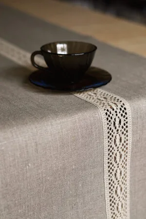 Natural tan linen table runner with a decorative linen lace trim through the middle.
