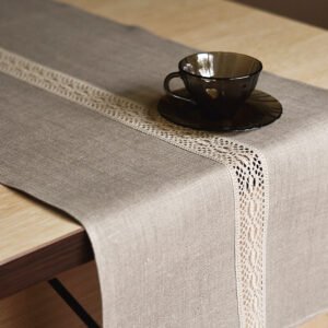 Natural tan linen table runner with a decorative linen lace trim through the middle.