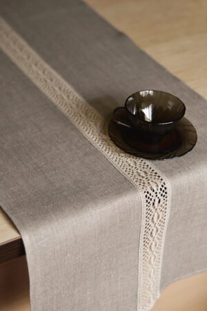 Natural tan linen table runner with a decorative linen lace trim through the middle.