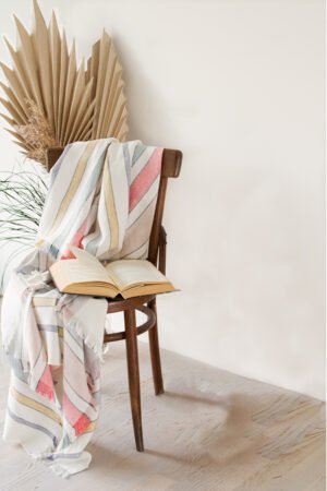 Soft linen blanket in off-white with colorful stripes used as a sofa cover. This versatile sofa throw blanket features decorative fringes on two edges, perfect for cozy home decor.